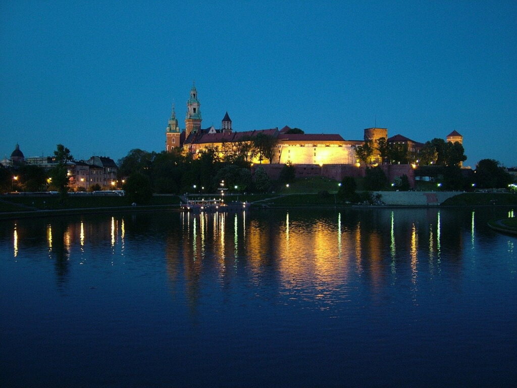 Oświetlony nocą Wawel odbijający się w wodach Wisły
