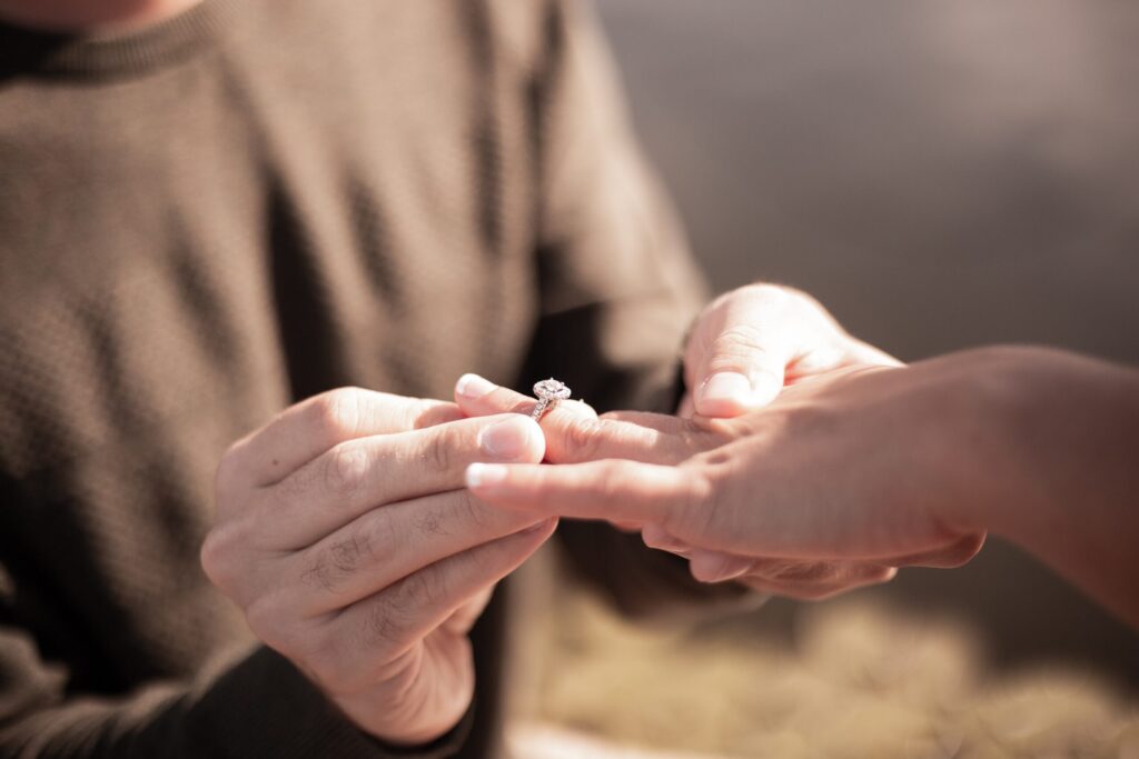 Man slips a gemstone ring onto another person's finger