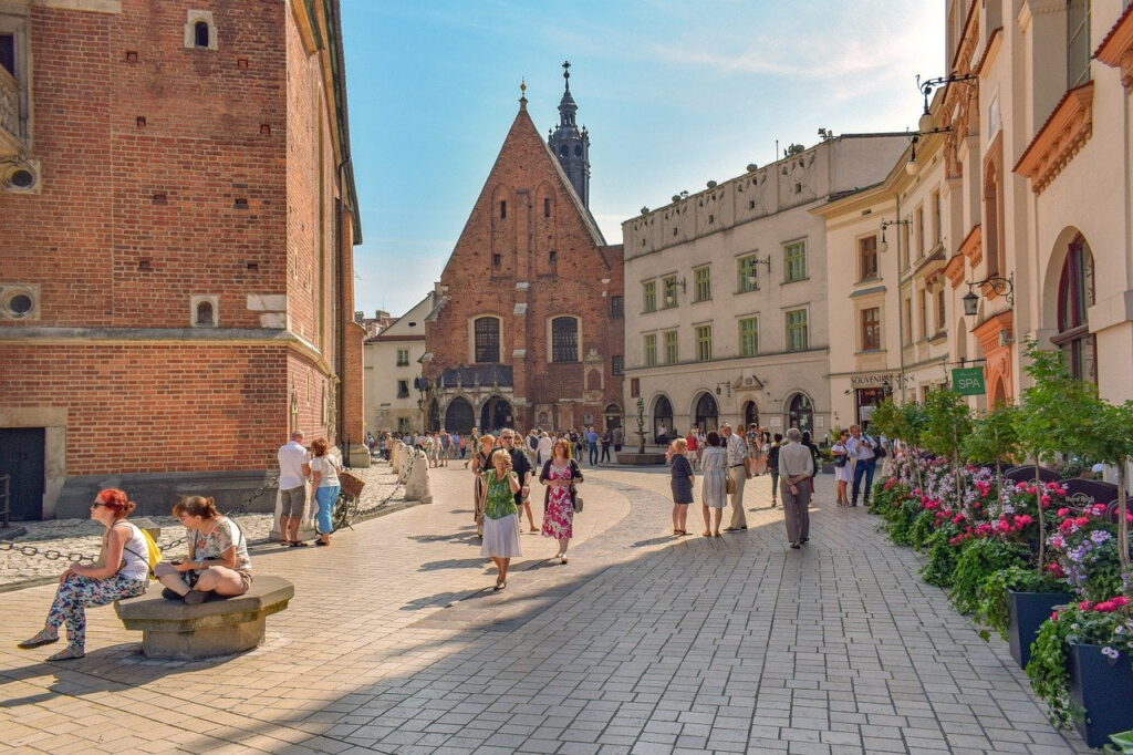 Spacerowicze na brukowanym placu przy ceglanym kościele w słoneczny dzień