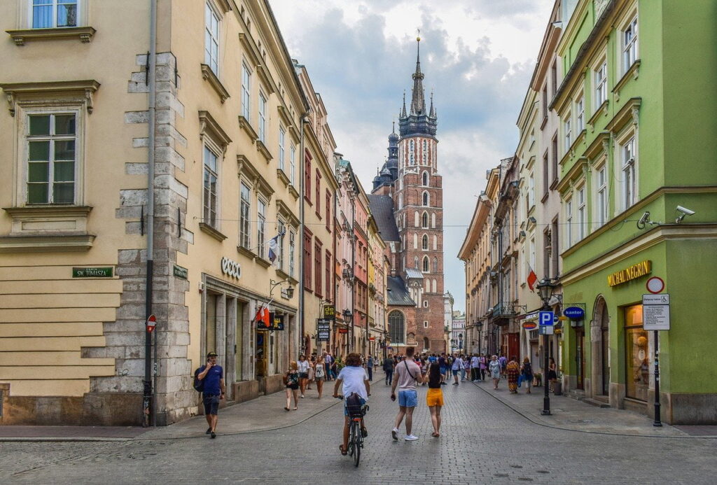 Ulica Floriańska z przechodniami i rowerzystą, w tle wieża Kościoła Mariackiego