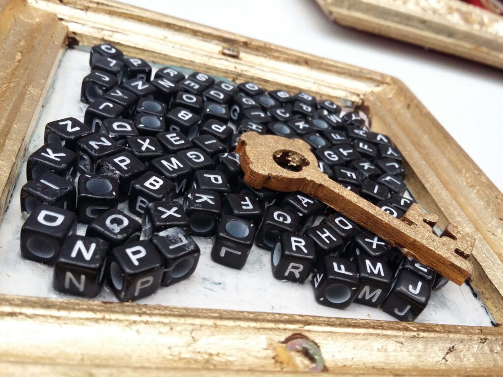 Black dice with letters and a gold key in a gilded frame