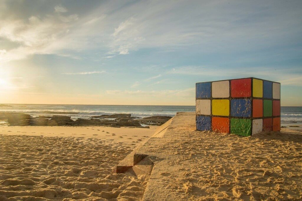 Large painted Rubik's Cube on a sandy beach by the sea