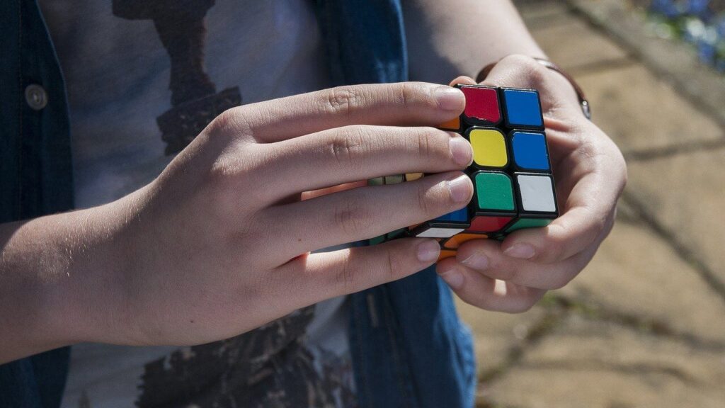 Hands solving a colourful Rubik's Cube