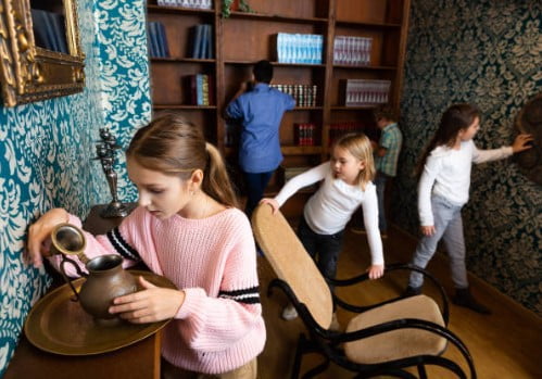 Children search for clues in a room full of shelving, a girl peers into a jug