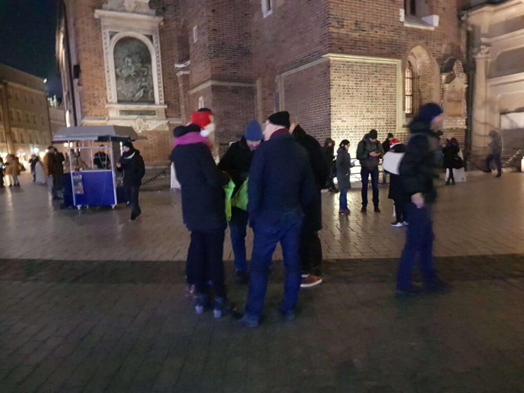 Group in winter hats in the evening on a square by a brick church